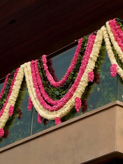 A detailed shot of the multi-colored floral garlands, showcasing the beautiful combination of pink roses, white tuberoses, and green leaves.