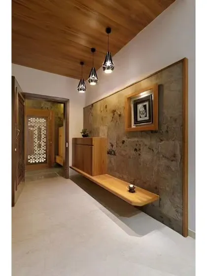 This long entryway features a floating wooden bench and cabinet against a textured stone wall. Modern pendant lights provide stylish illumination for the hallway.