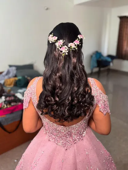 A half-up style for a gown, featuring bouncy curls and a delicate crown of pink and white flowers.