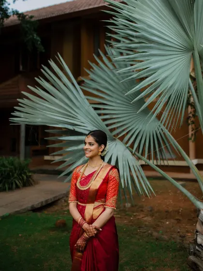 A smile that lights up the day. This candid bridal portrait captures the bride's infectious happiness and natural beauty in her stunning red saree.