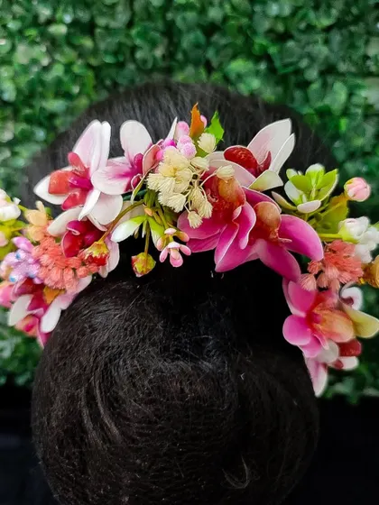 A lovely hair veni featuring a mix of pink and white orchids and other delicate blossoms. This accessory adds a fresh and romantic touch to any bridal hairstyle.