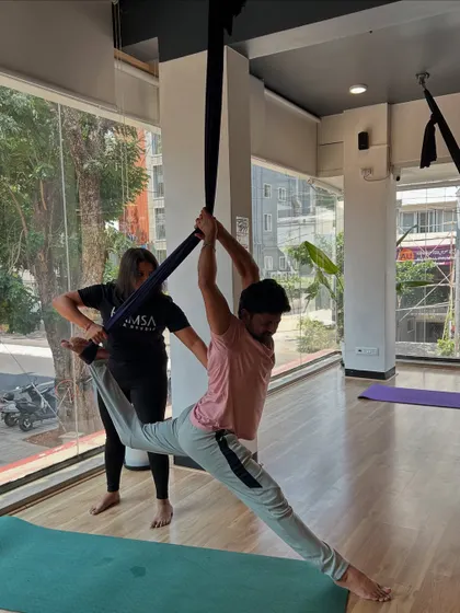An instructor provides hands-on assistance to help a student achieve a full split in the aerial hammock, demonstrating our commitment to personalized guidance and safety.