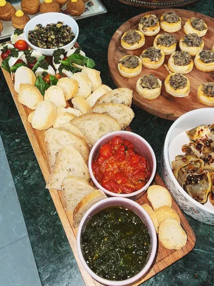 Our Caprese-style grazing board is a fresh and light option. It features fresh mozzarella, cherry tomatoes, basil pesto, tomato confit, and slices of baguette for a build-your-own bruschetta experience.