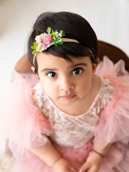 An overhead shot of a baby girl in a lovely pink tulle dress, looking directly at the camera for a captivating portrait.
