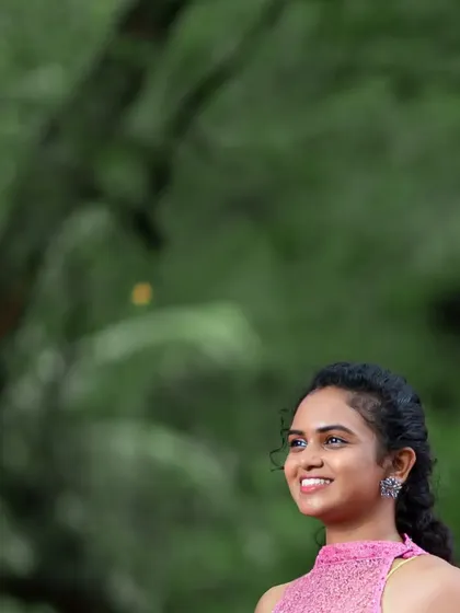 A close-up portrait showcasing the happy mom-to-be and the elegant halter-style top of this popular pink maternity rental gown.