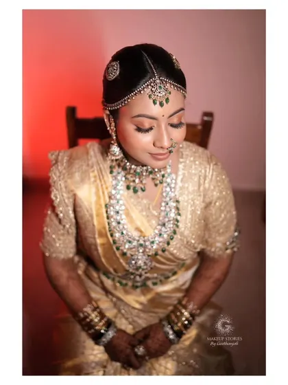 The epitome of beauty, Nidhi Venugopal for her wedding. This portrait, with its dramatic lighting, highlights the flawless finish of her makeup and the sparkle of her diamond and emerald jewelry.