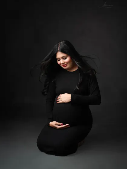 A quiet and contemplative solo portrait. Kneeling on the floor, the mom-to-be cradles her bump in this beautiful, low-key shot.