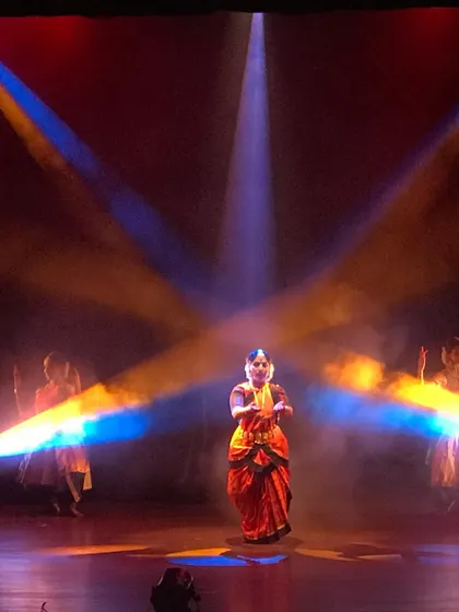 A soloist takes center stage in 'Akhandalaya', framed by dramatic cross-lighting. My productions often balance powerful group choreography with moments of focused, individual expression.