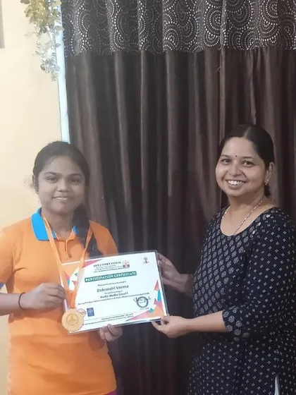 A student from Bellary receives her medal and certificate with a proud smile. These competitions are a great way for children to gain confidence and experience a sense of accomplishment.