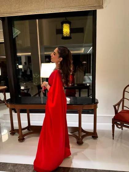 A side profile of my self-designed red saree. The cape-like drape adds a modern touch to a classic silhouette, making it perfect for a cocktail party or reception.