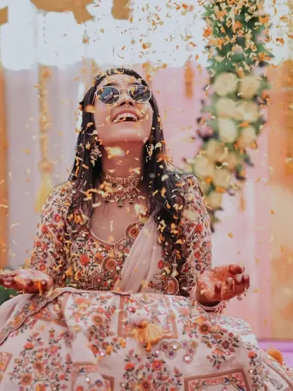 A cool, modern bride enjoying a shower of confetti during her Mehendi or Haldi ceremony. This shot is all about attitude and fun.