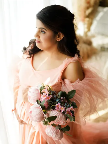 A close-up portrait highlighting the delicate details of the gown and the mother's serene expression.