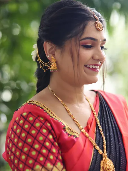 A smiling profile of Deepika. Her hair is styled in a simple, traditional braid with a modern twist, and her makeup is fresh and bright.