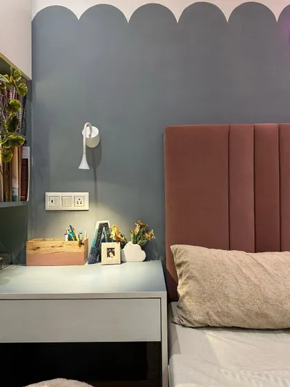 A detailed shot of the bedside study nook, showing how a small space can be made highly functional with a simple desk and good lighting.