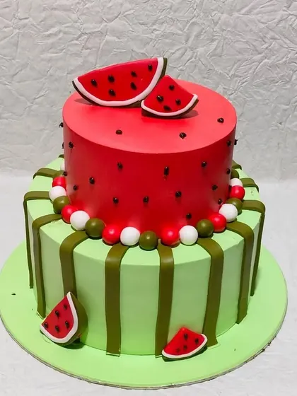 A refreshing watermelon-themed cake. The two-tiered design mimics the look of a real watermelon, inside and out, perfect for a summer party.