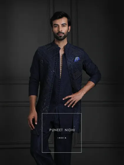 This outfit is an expression of legacy. A navy open jacket with detailed geometric embellishments, complemented by a loop-buttoned tunic and textured bell-bottom lowers.