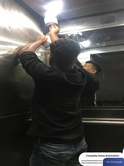 Even in tight spaces like an elevator, we ensure a professional installation. This technician is installing a camera to provide security and monitoring for residents.