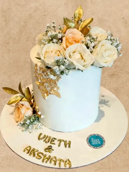 Another view of this elegant engagement cake, showcasing the beautiful arrangement of fresh flowers and gold leaf details. It's a testament to how simple elements can create a stunning effect.