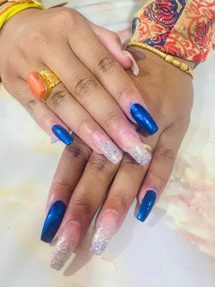 A "bluetiful" combination of deep blue chrome and sparkling silver glitter on long coffin nails.