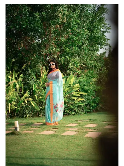 A duplicate of image 10, this full-length shot shows the elegance of the saree against a lush, natural backdrop.