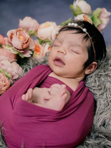 A floral embrace. This swaddled baby, nestled in a bed of fur and flowers, looks like a precious gem.