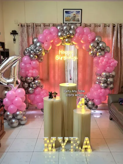 A pink and silver balloon arch with a large foil number '4' for Myra's 4th birthday.