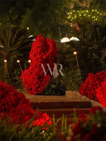 Another view of the path of red blooms, leading guests towards the main event space. The organic shapes of the floral sculptures contrast beautifully with the structured stone path.