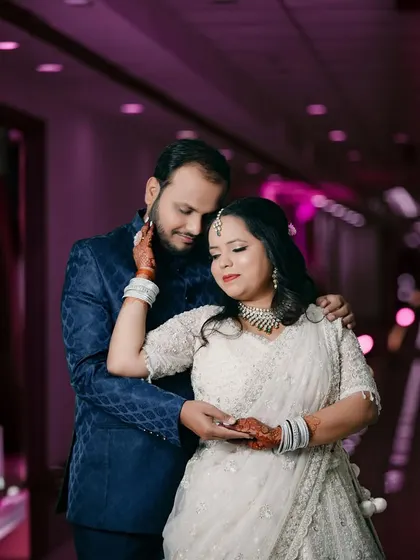 An intimate reception portrait where the groom gently caresses the bride's face. The soft purple lighting and their tender expressions create a romantic and cinematic feel.
