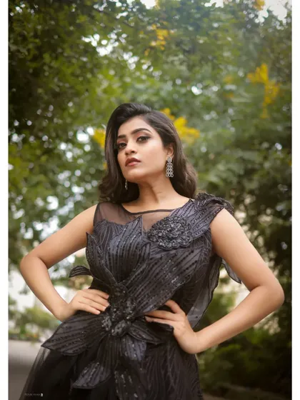 A powerful pose in the black evening gown. The intricate floral detail on the bodice adds a unique, high-fashion element to this stunning dress.