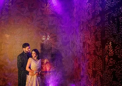 A dramatic photo of the couple at their Sangeet in Kochi. The textured gold walls and moody purple lighting created a perfect, intimate photo opportunity away from the main stage.