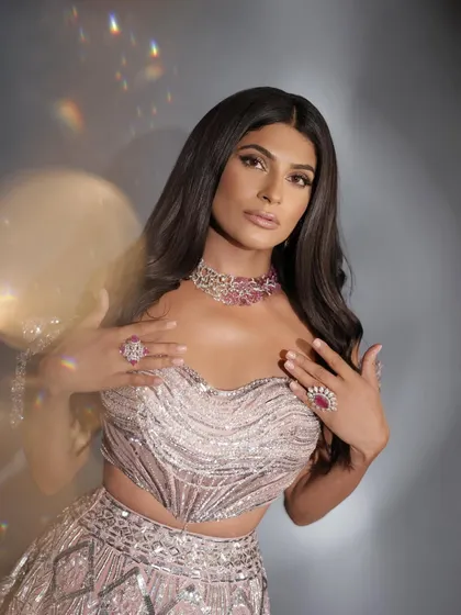 A stunning close-up of Farhana Bodi. The hair is styled in soft, voluminous waves, and the makeup enhances her natural beauty with a touch of sparkle.