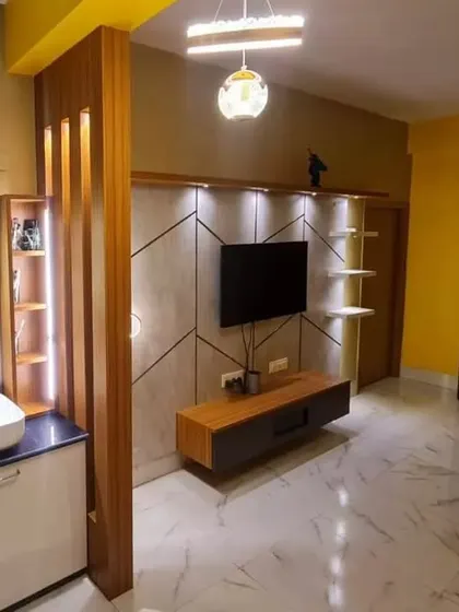 A wide shot of the living and dining area in a Kolkata home, showing the open layout and the cohesive design of the TV unit and vanity.