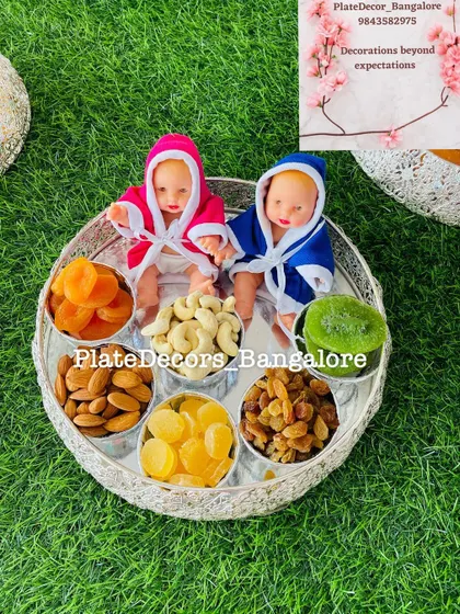 Another view of my twin-themed dry fruit platter, showing the arrangement of almonds, cashews, raisins, and dried apricots around the two dolls.