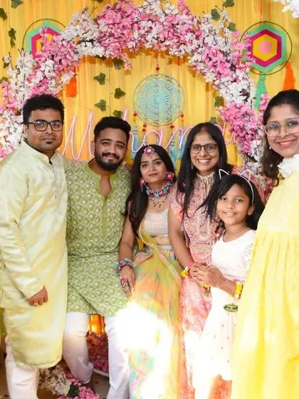 Friends and family in coordinated yellow outfits gather for a group photo with the happy couple.