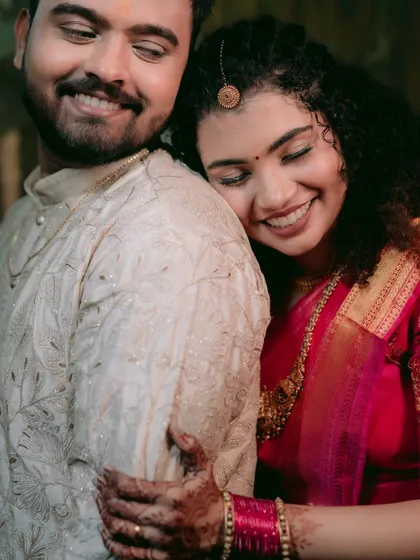 A tender embrace, capturing the bride's joyful smile and the intricate details of her saree and jewelry.