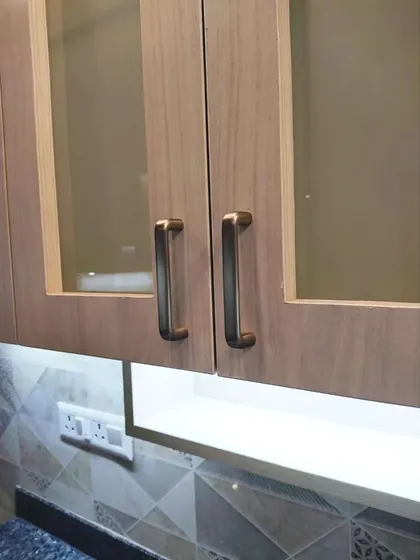 A close-up of the frosted glass cabinet doors and brushed metal handles. These small details contribute to the overall modern and sophisticated look of the kitchen.