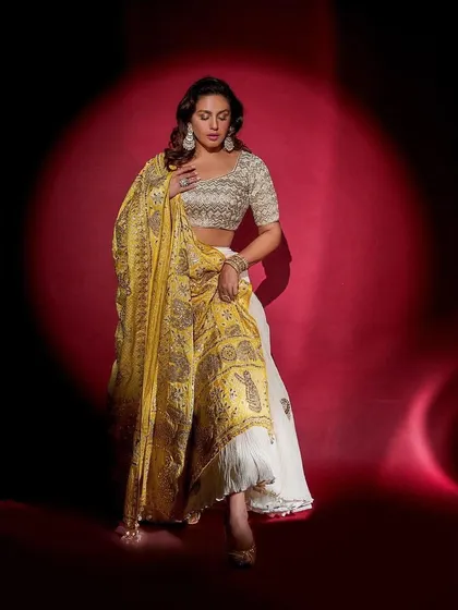 A full-length view of the Faabiiana lehenga, showing how the rich yellow dupatta drapes beautifully over the ivory skirt.