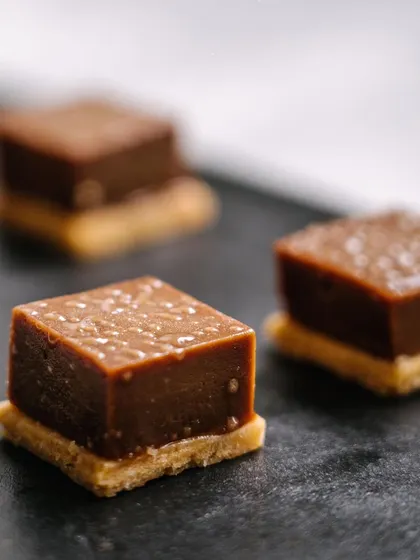 Milk chocolate fudge on a vanilla sable biscuit. This sweet canapé offers a delightful contrast of creamy fudge and a crisp, buttery base.
