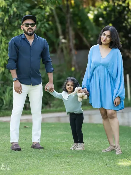 A happy family of three enjoying a day in the park. The daughter holds her parents' hands, creating a lovely portrait of togetherness and fun.