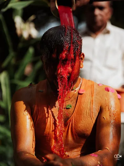 A dramatic close-up as red colored water is poured over the groom's head during a lively Haldi ceremony.