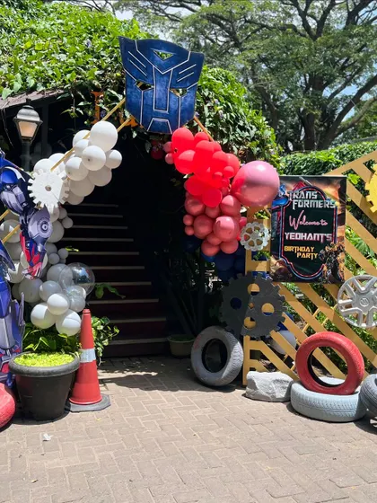 The entrance to a Transformers-themed birthday party. The archway is decorated with red and white balloons, tires, and the Autobot logo, immediately immersing guests in the theme.