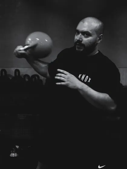 A dramatic, black and white photo of a coach mid-kettlebell flow, capturing the intensity and focus of our training.