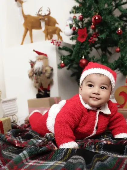 A crawling baby dressed as Santa makes for an adorable action shot during our Christmas session. The festive background is filled with presents and holiday cheer.