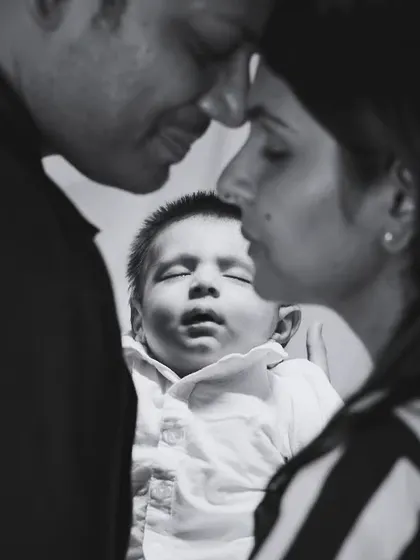 A black and white portrait capturing the intimate bond between parents and their newborn.