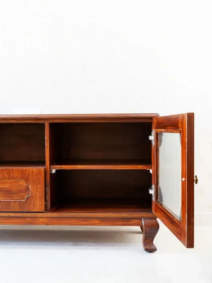A detail of the TV console's interior, showing the ample storage space behind the glass door.