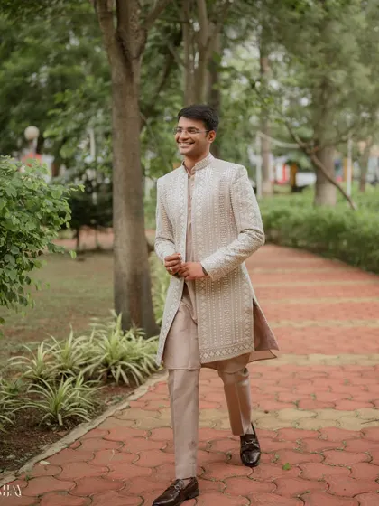 A candid, walking portrait of the groom with a bright, genuine smile. This shot captures his personality and dapper style in a relaxed, outdoor setting.