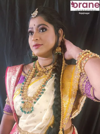 A beautiful profile shot showcasing a traditional bridal hairstyle. The hair is elegantly styled to support the heavy jewelry and veil, a key consideration in our bridal hairstyling training.