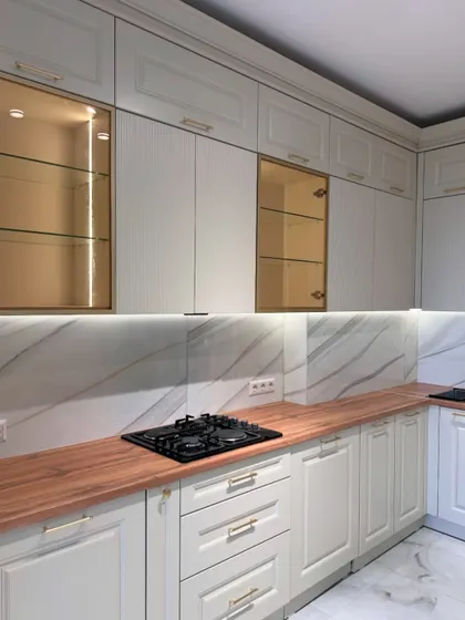 An overall view of the white and wood classic kitchen, showing the L-shaped layout and the balance between the solid and glass-fronted cabinets.