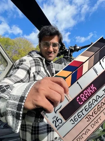 A crew member with the "Crakk" clapperboard in front of a helicopter. This image perfectly captures the scale and excitement of working on a big-budget action film.