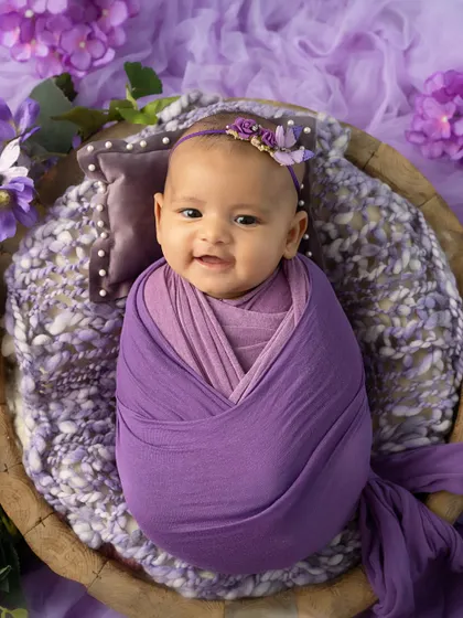 The sweetest smile. This 3-month-old is happy and content, wrapped snugly in a lavender swaddle.